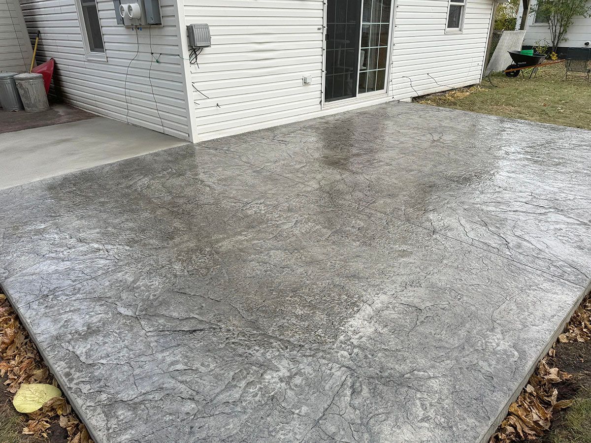 A gray concrete patio in front of a white house
