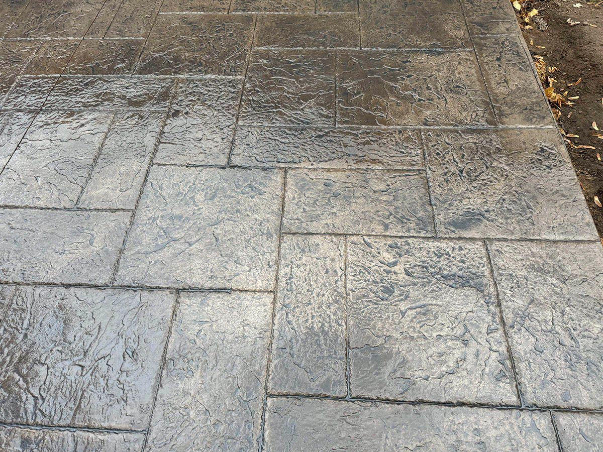 A close up of a concrete walkway with a brick pattern