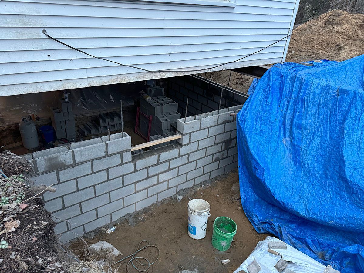 A brick wall is being built under a house