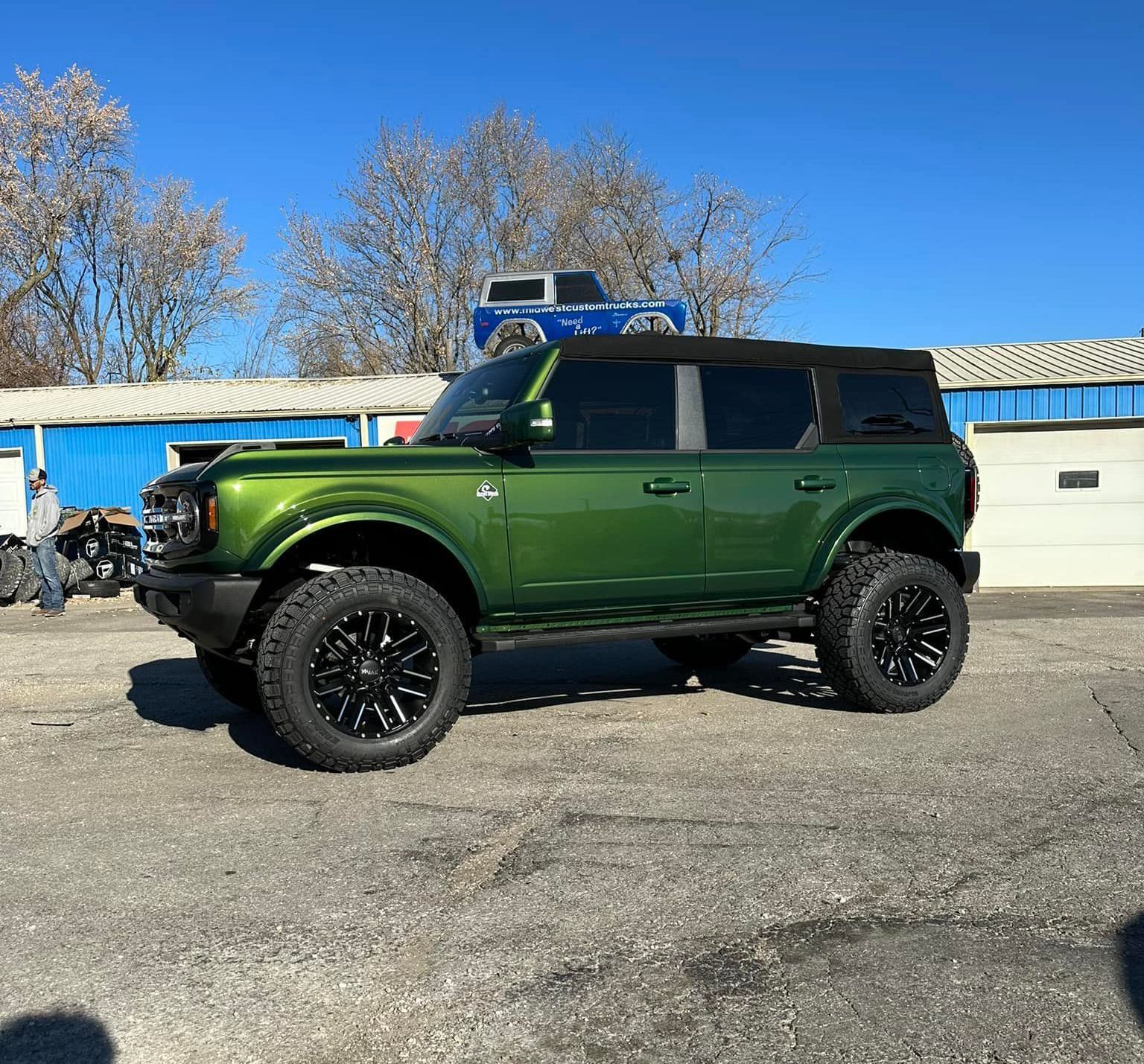 A green ford bronco is parked in a parking lot.