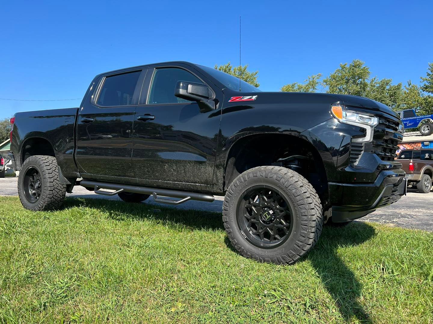 A black truck is parked on top of a lush green field.