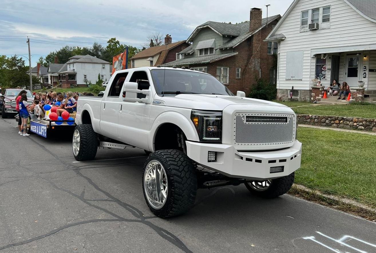 A white truck is pulling a float down a street in a parade.