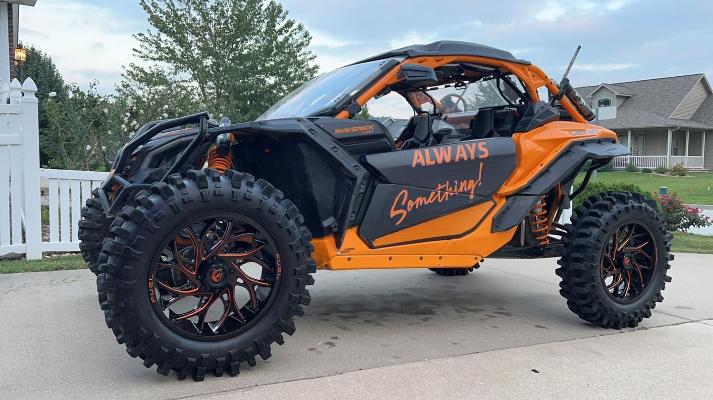 An orange and black atv is parked in a driveway.