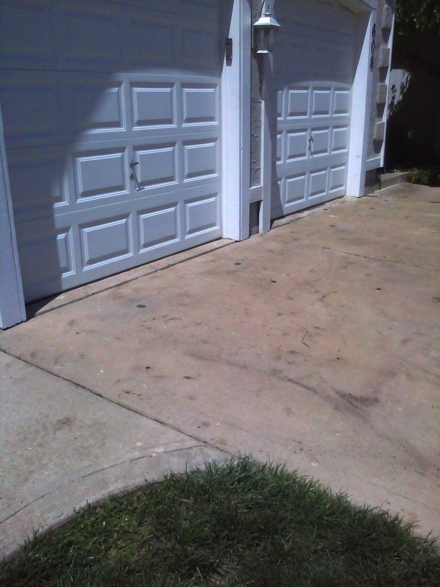 A row of white garage doors on a concrete driveway