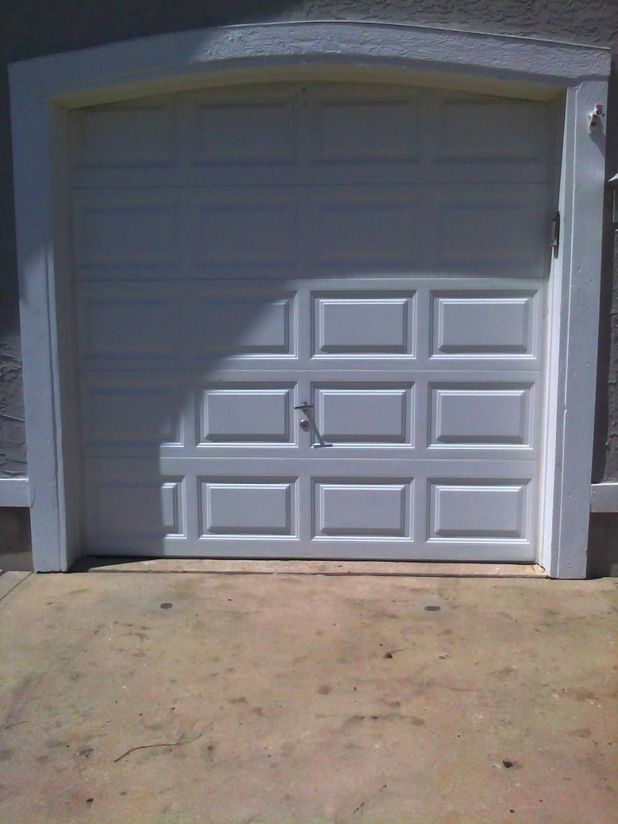 A white garage door is open to a concrete driveway