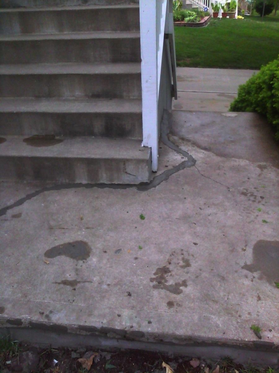 A concrete walkway with stairs leading up to a house