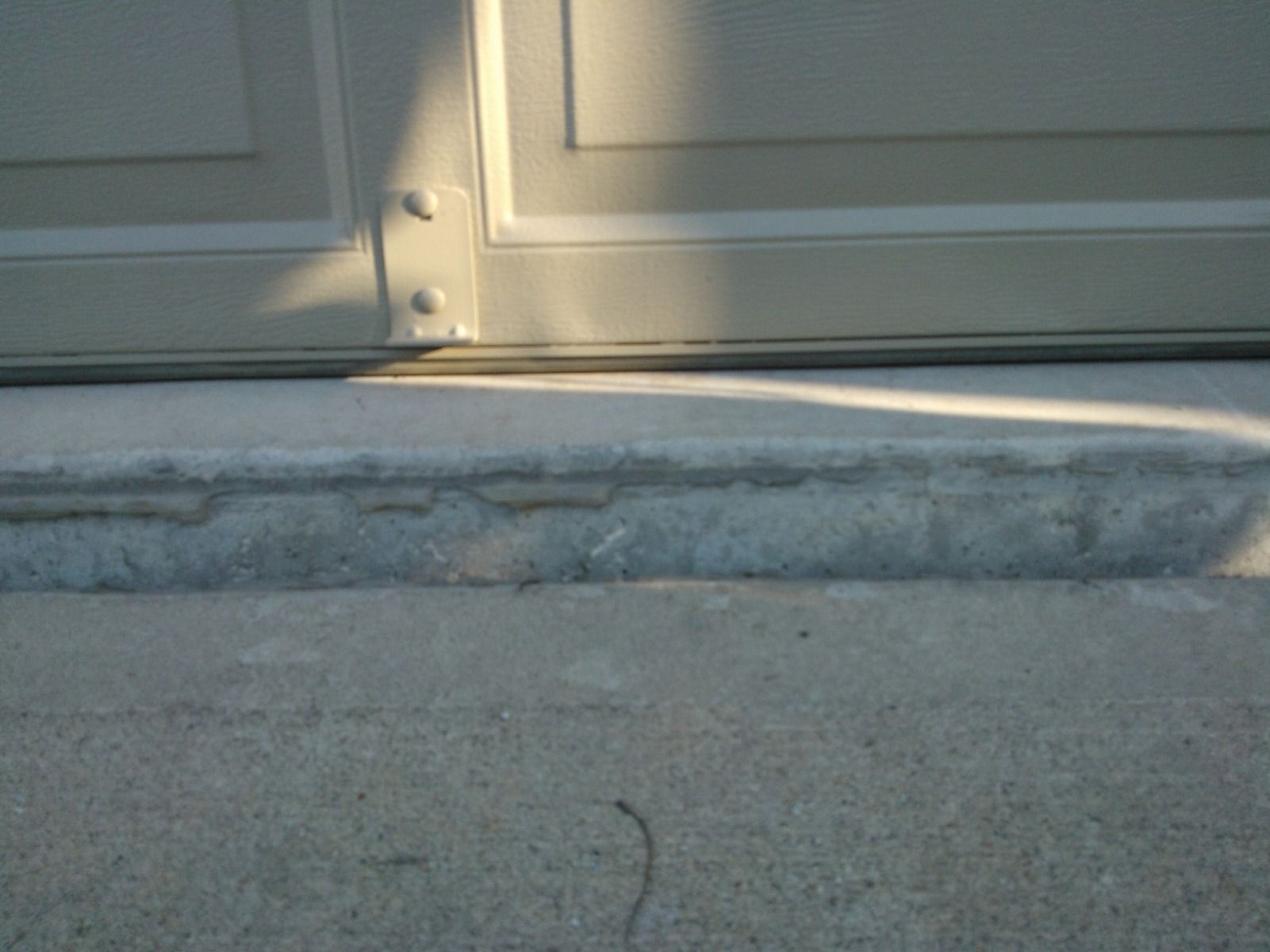A close up of a garage door with a concrete ramp underneath it