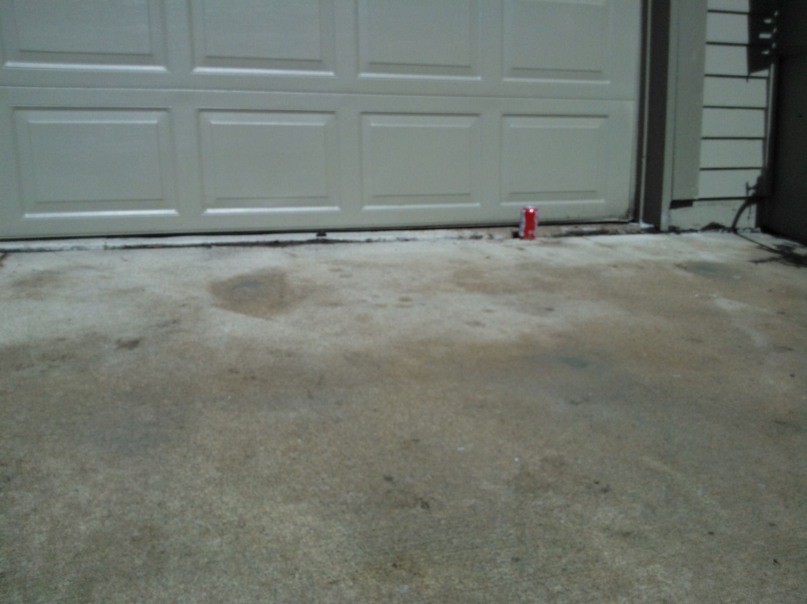 A can of coke sits on the ground in front of a garage door
