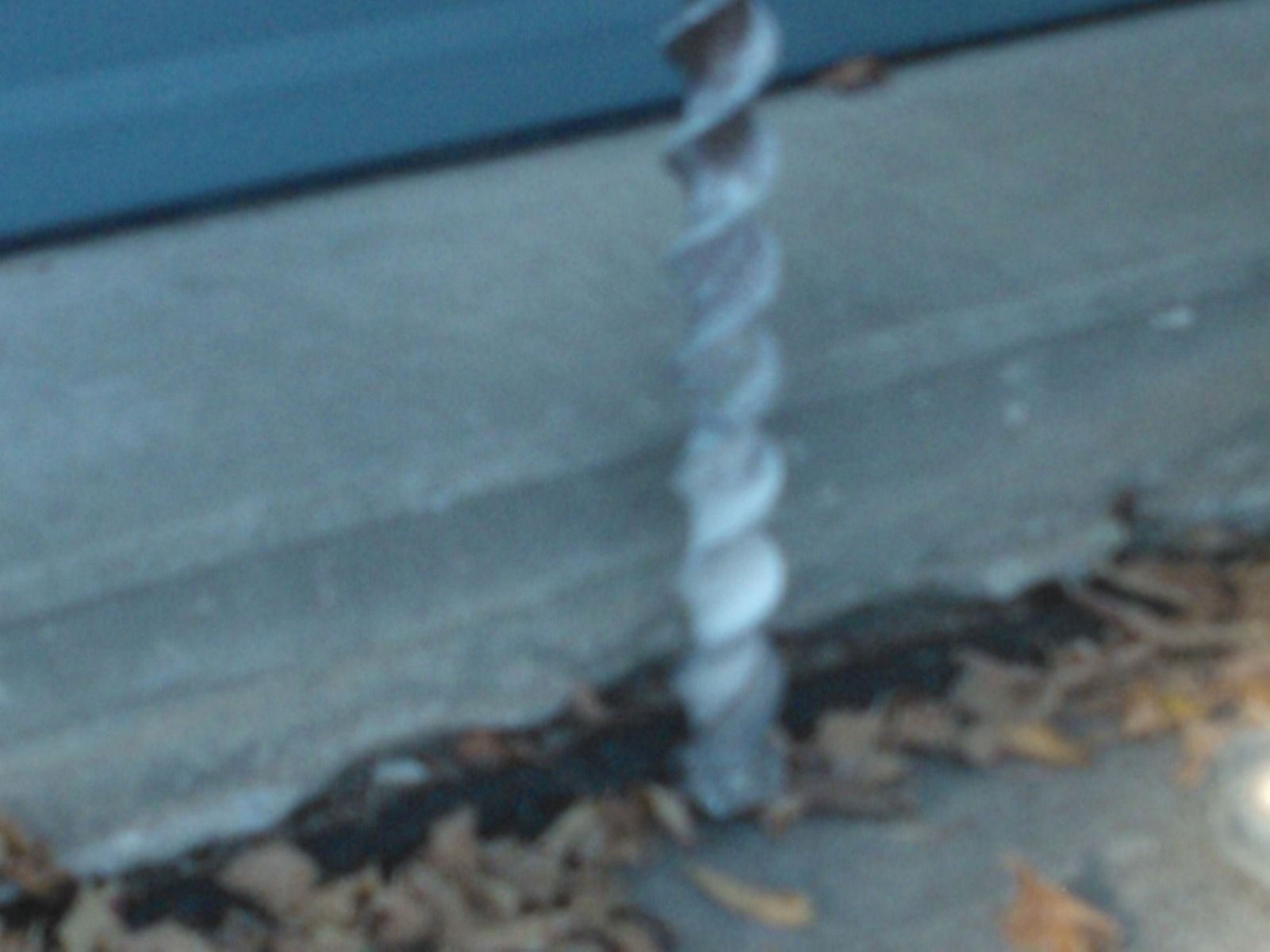A twisted metal pole with leaves on the ground