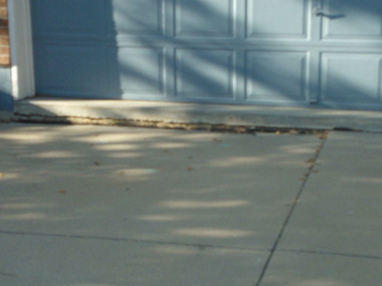 A concrete driveway with a blue garage door in the background