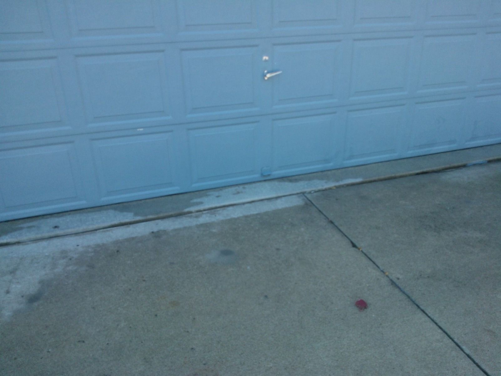 A blue garage door is sitting on a concrete sidewalk.