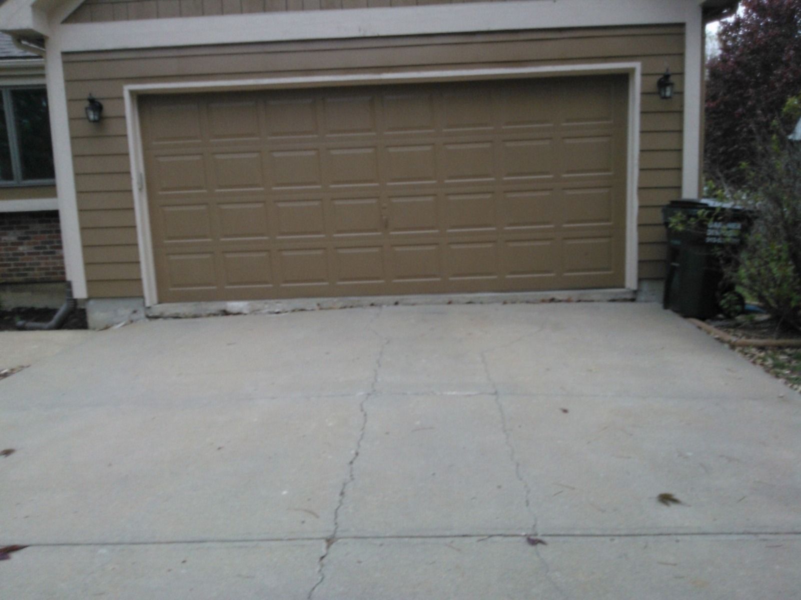 A brown garage door is open in front of a house