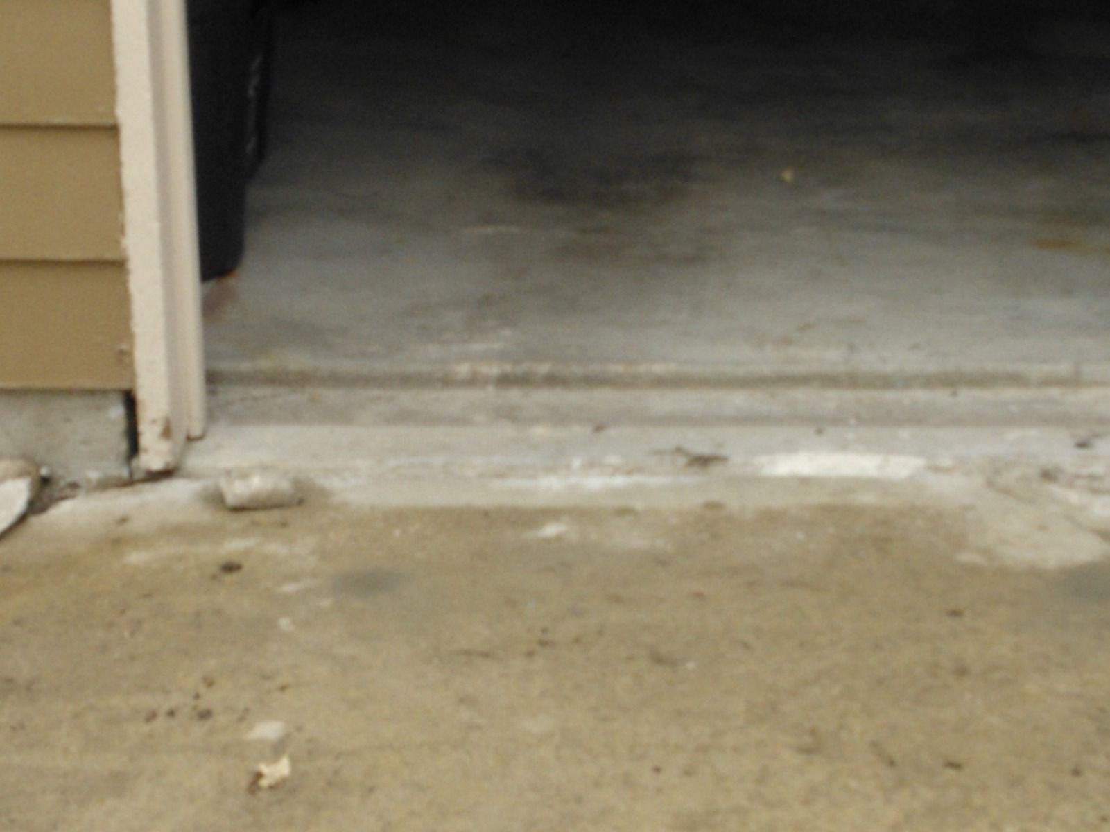 A drainpipe is attached to a sidewalk next to a house
