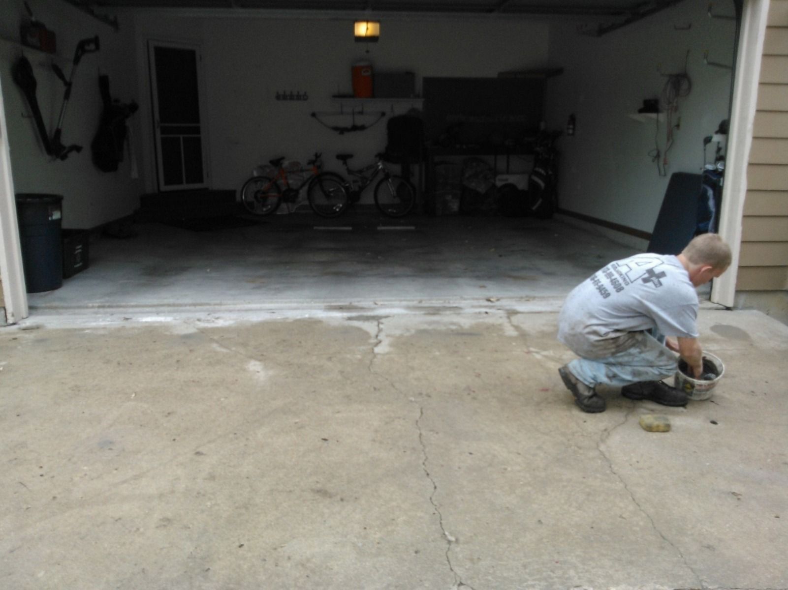 A man is kneeling down in front of a garage door