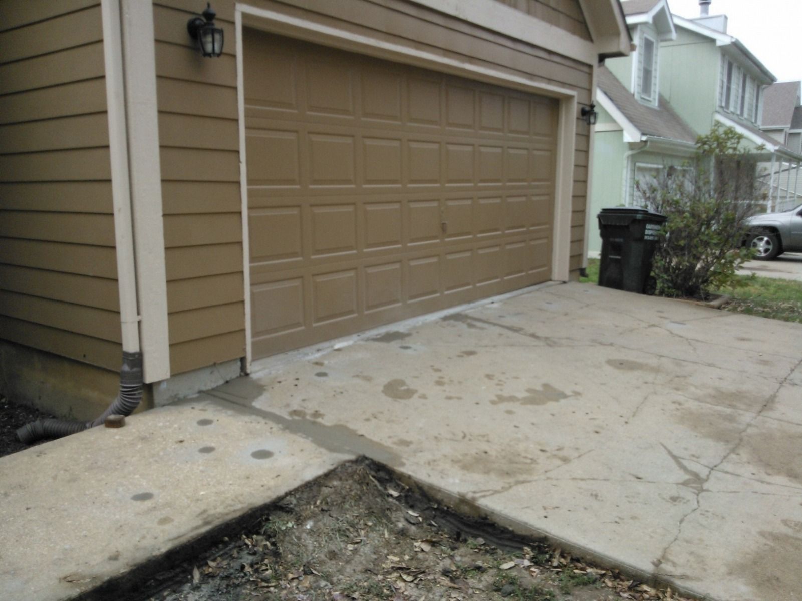 A car is parked in front of a brown garage door