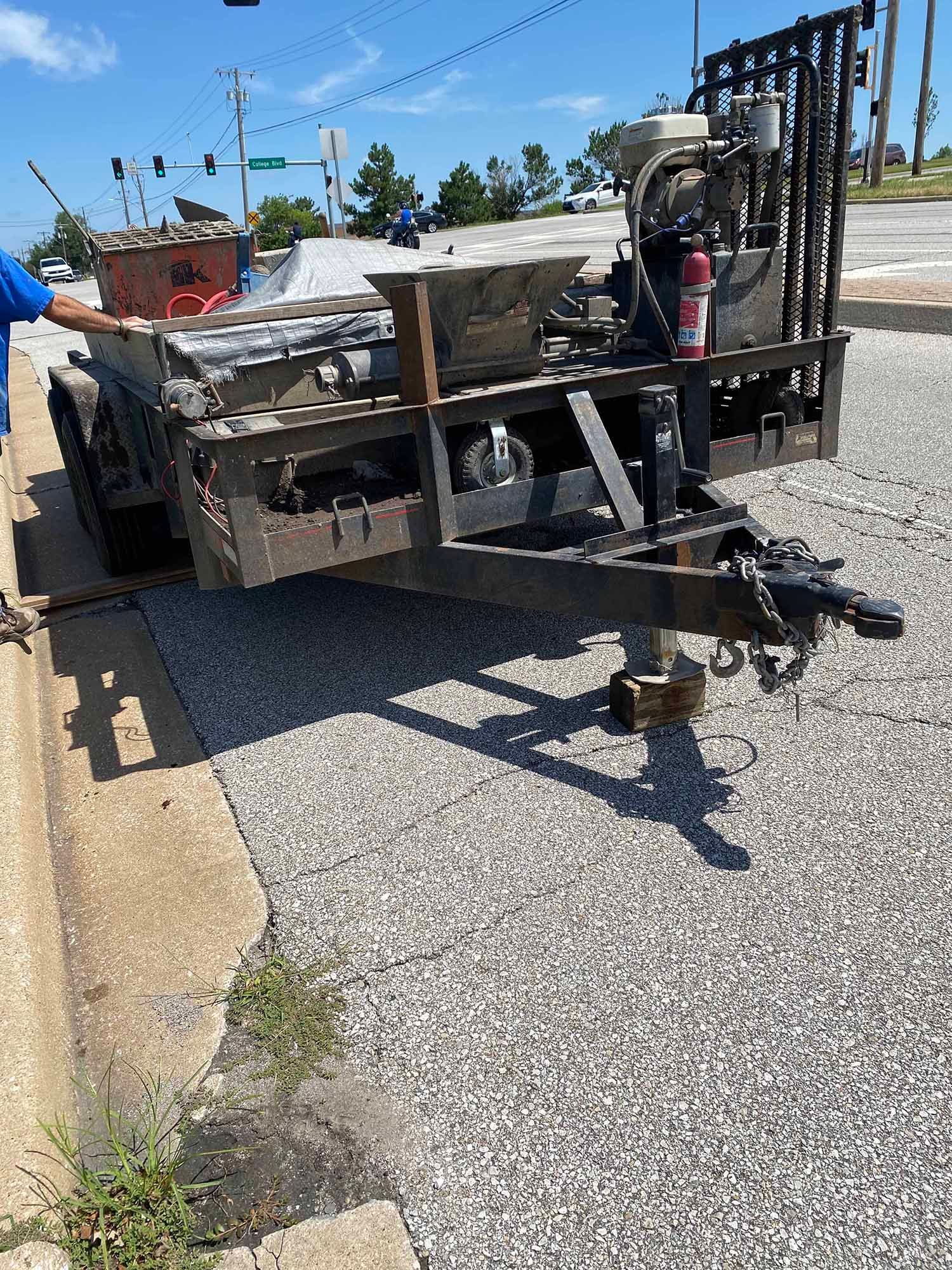 A trailer is parked on the side of the road next to a curb.