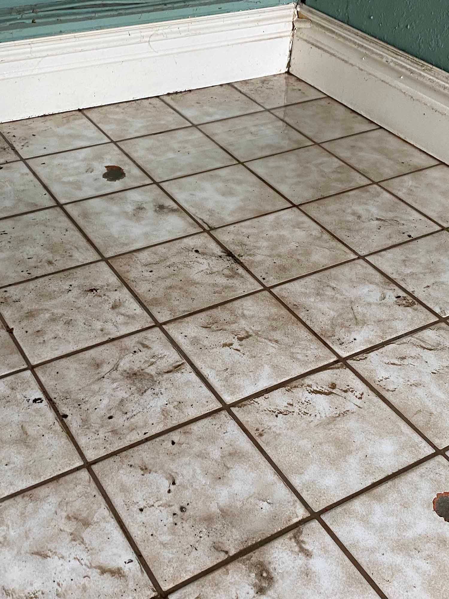 A close up of a dirty tile floor in a room.