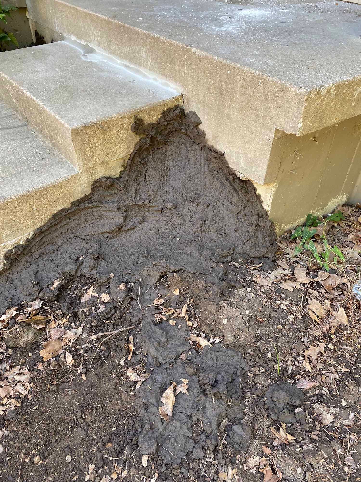 A pile of dirt is sitting on the ground next to a concrete staircase.