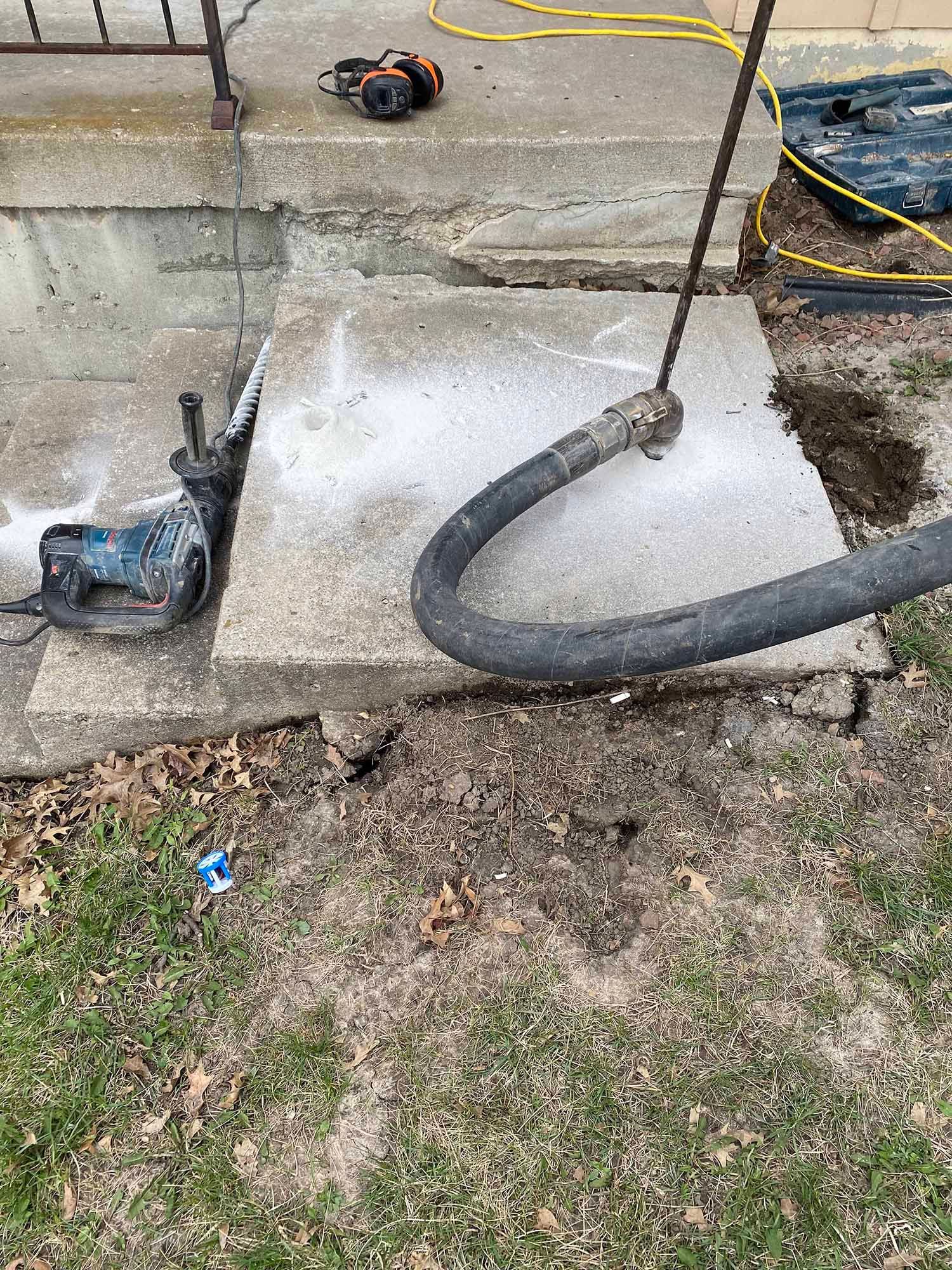 A hose is being used to pump concrete into a hole in the ground.