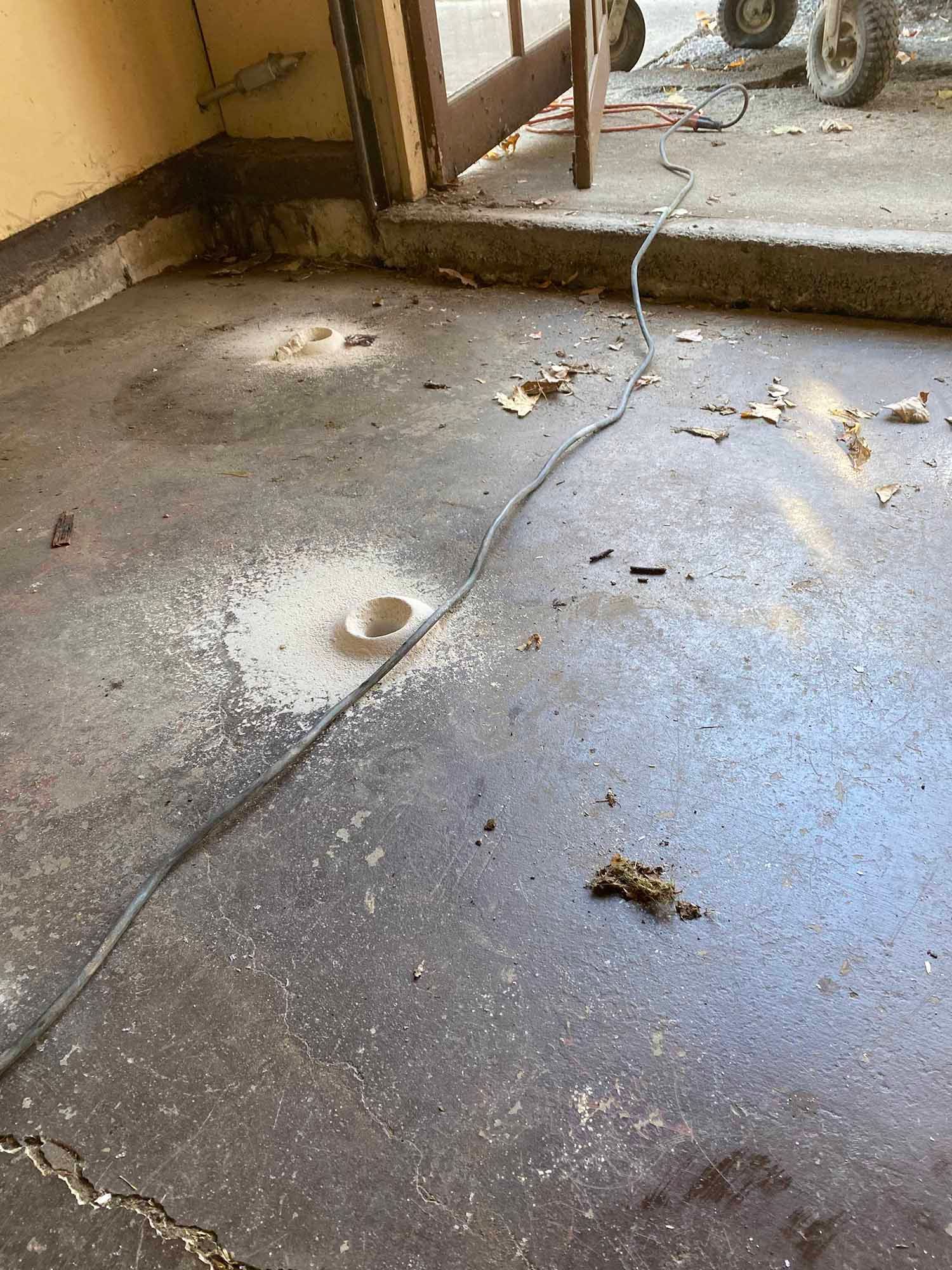 A dirty concrete floor with a power cord laying on it.