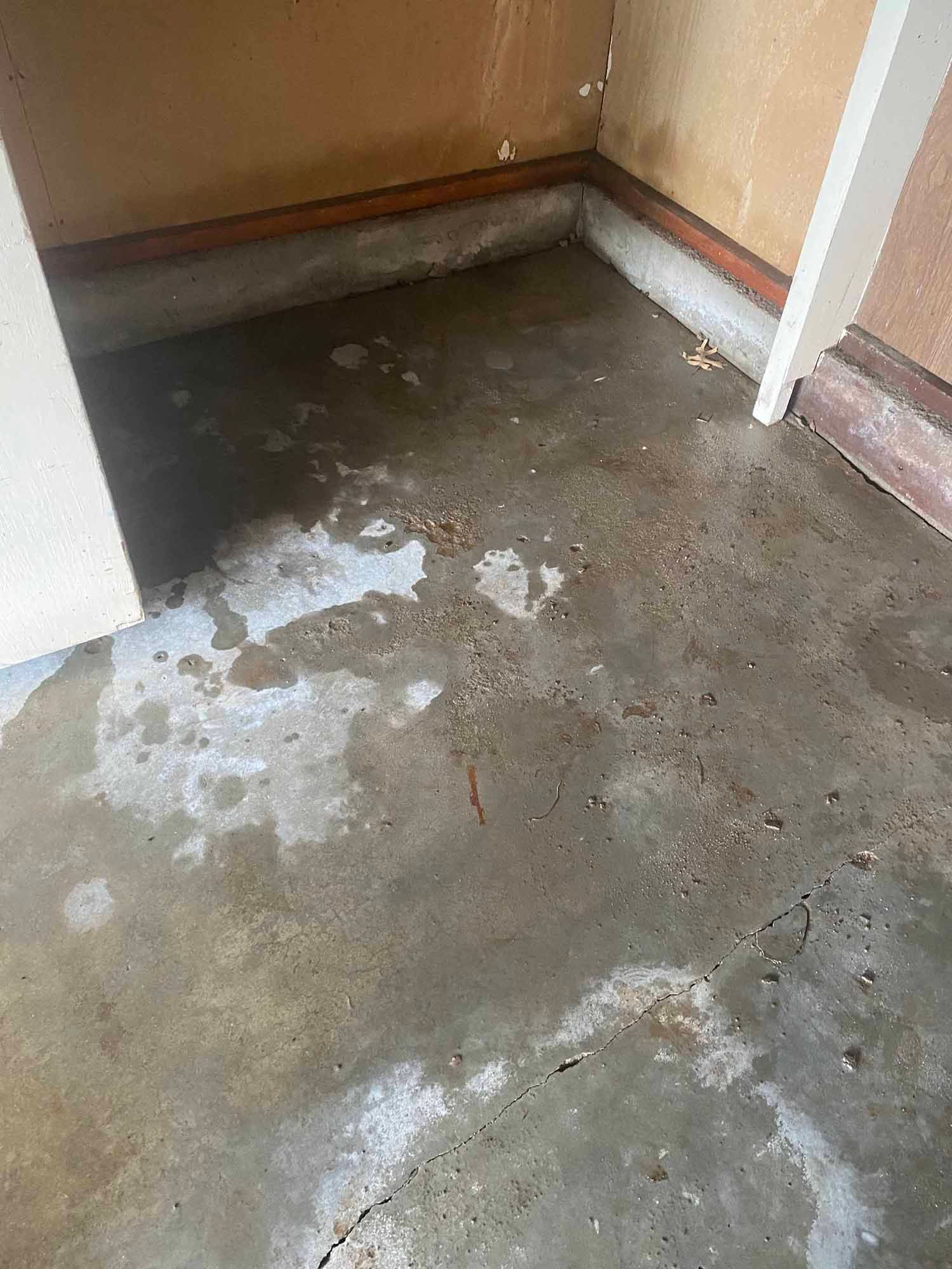 A dirty concrete floor in a room next to a wall.