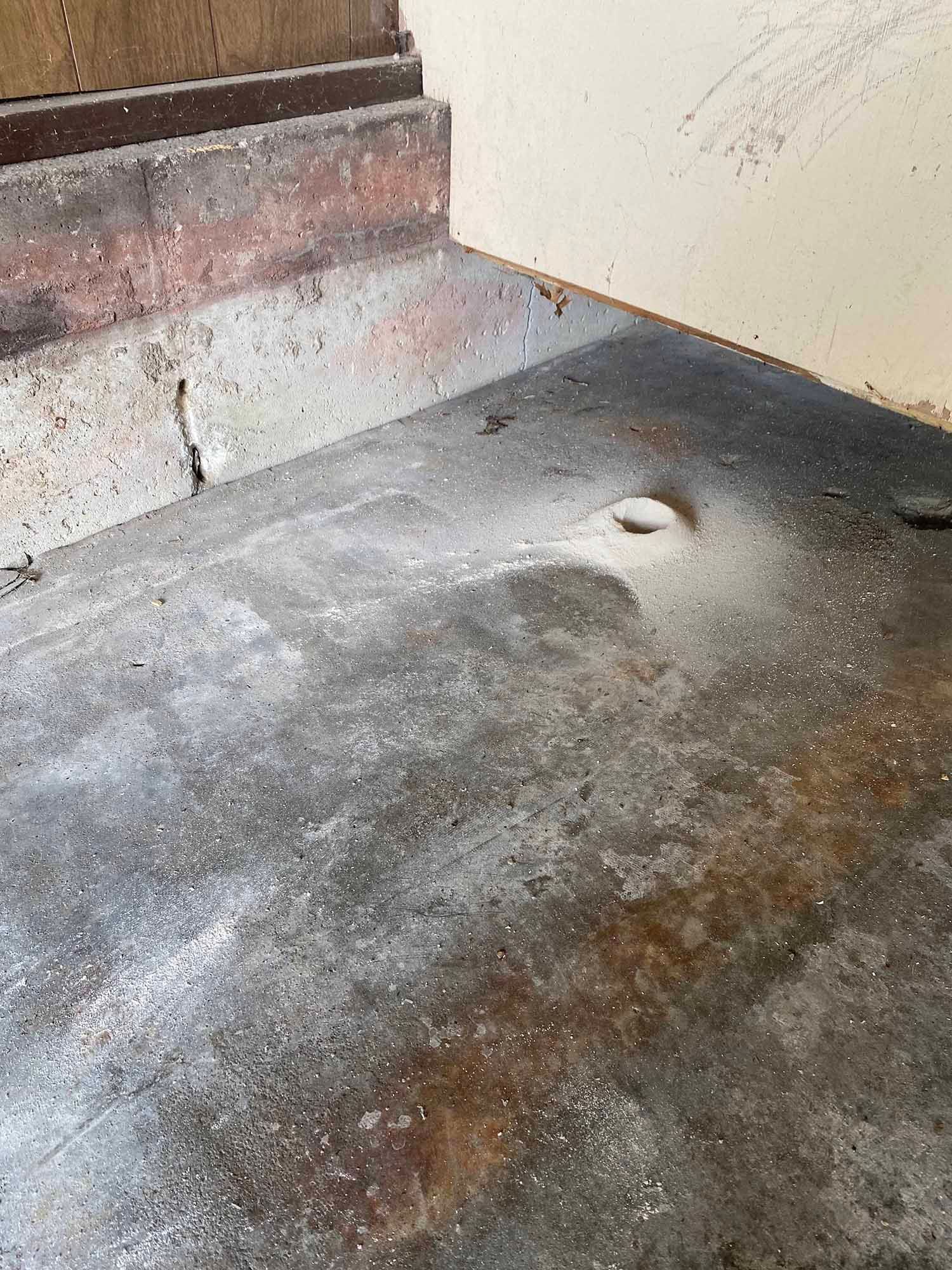 A close up of a concrete floor with a hole in it.