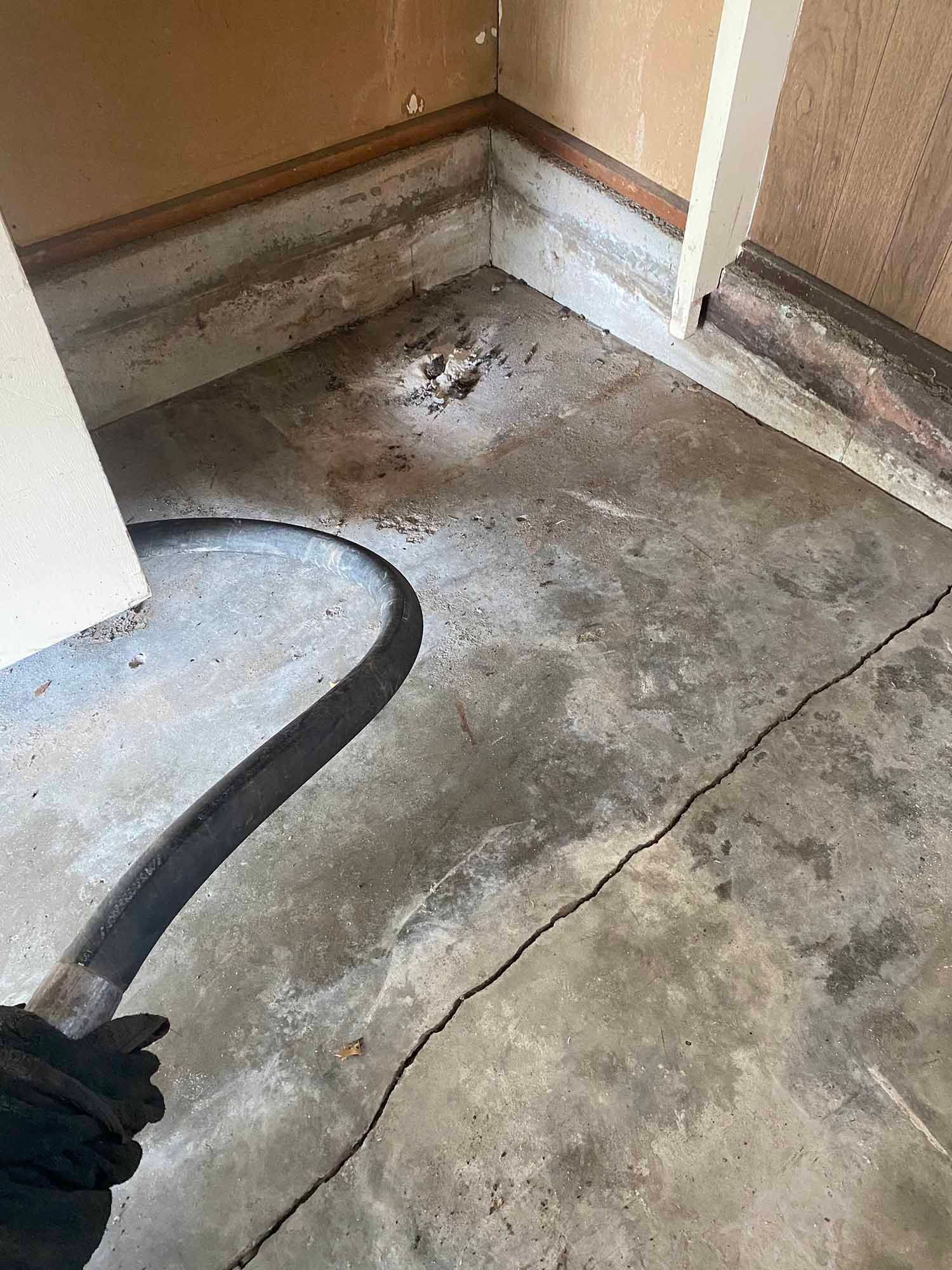 A person is vacuuming a concrete floor in a garage.