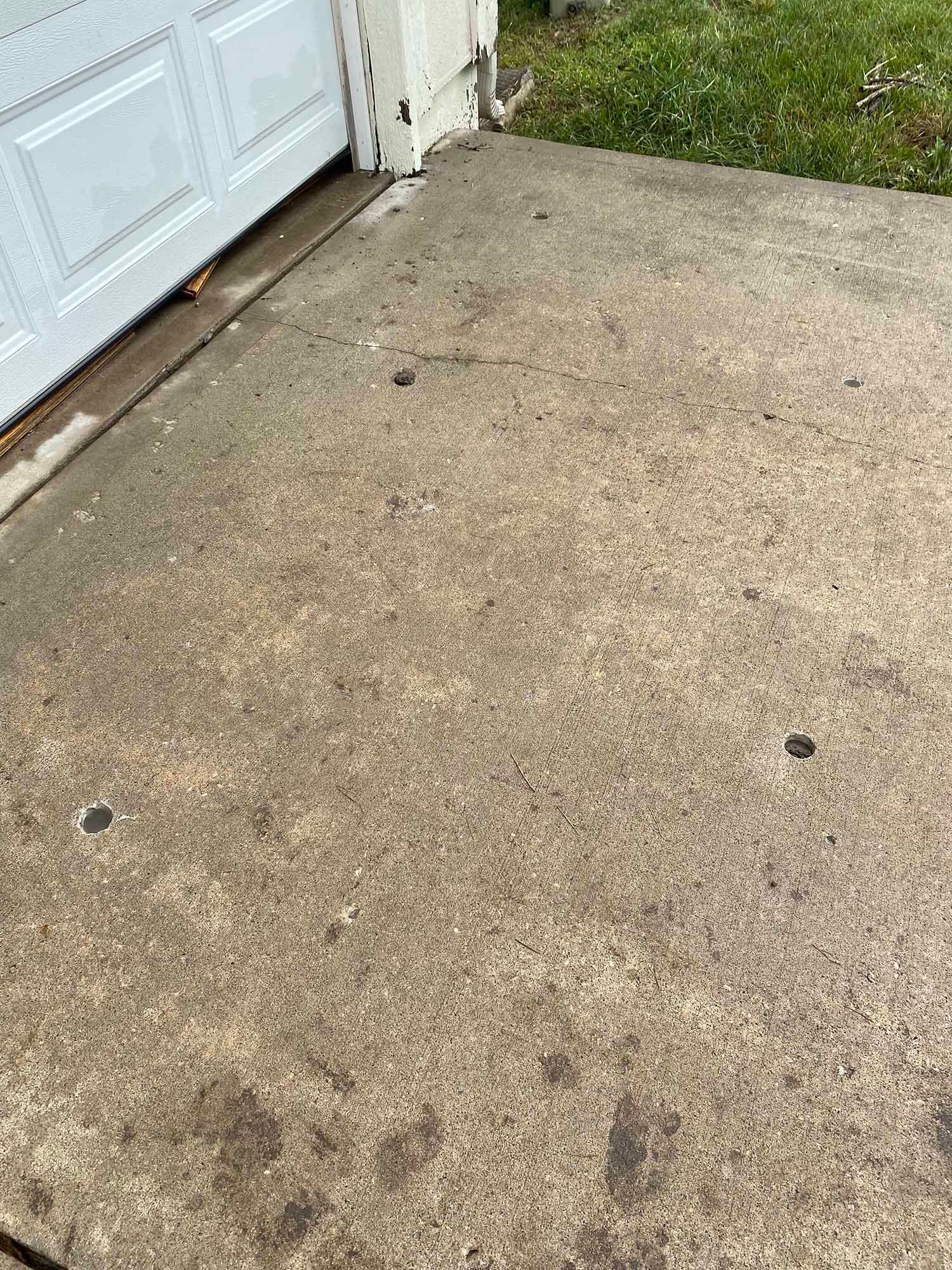 A dirty concrete driveway next to a garage door.