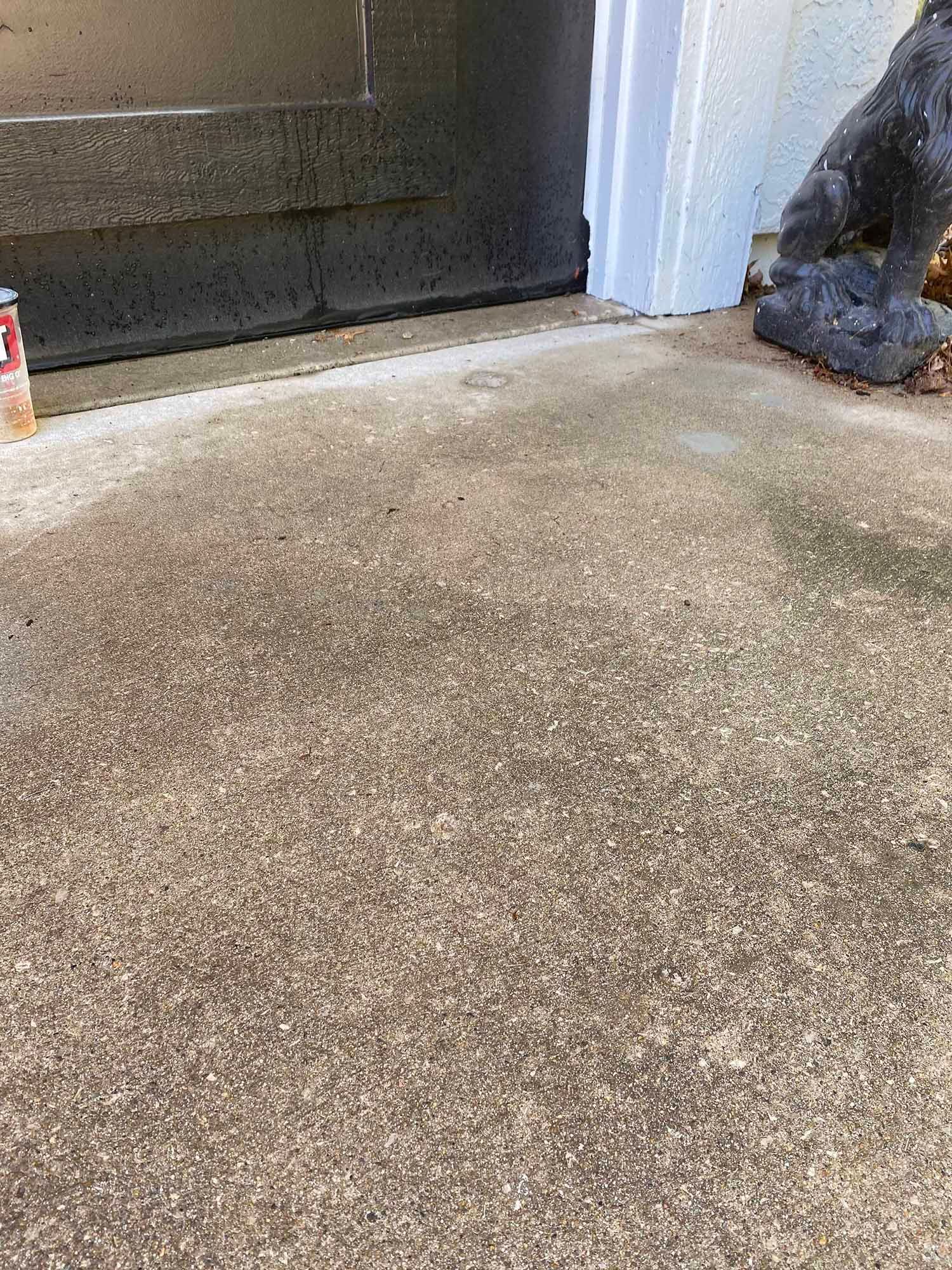 A statue of a gorilla is sitting on a concrete floor next to a door.