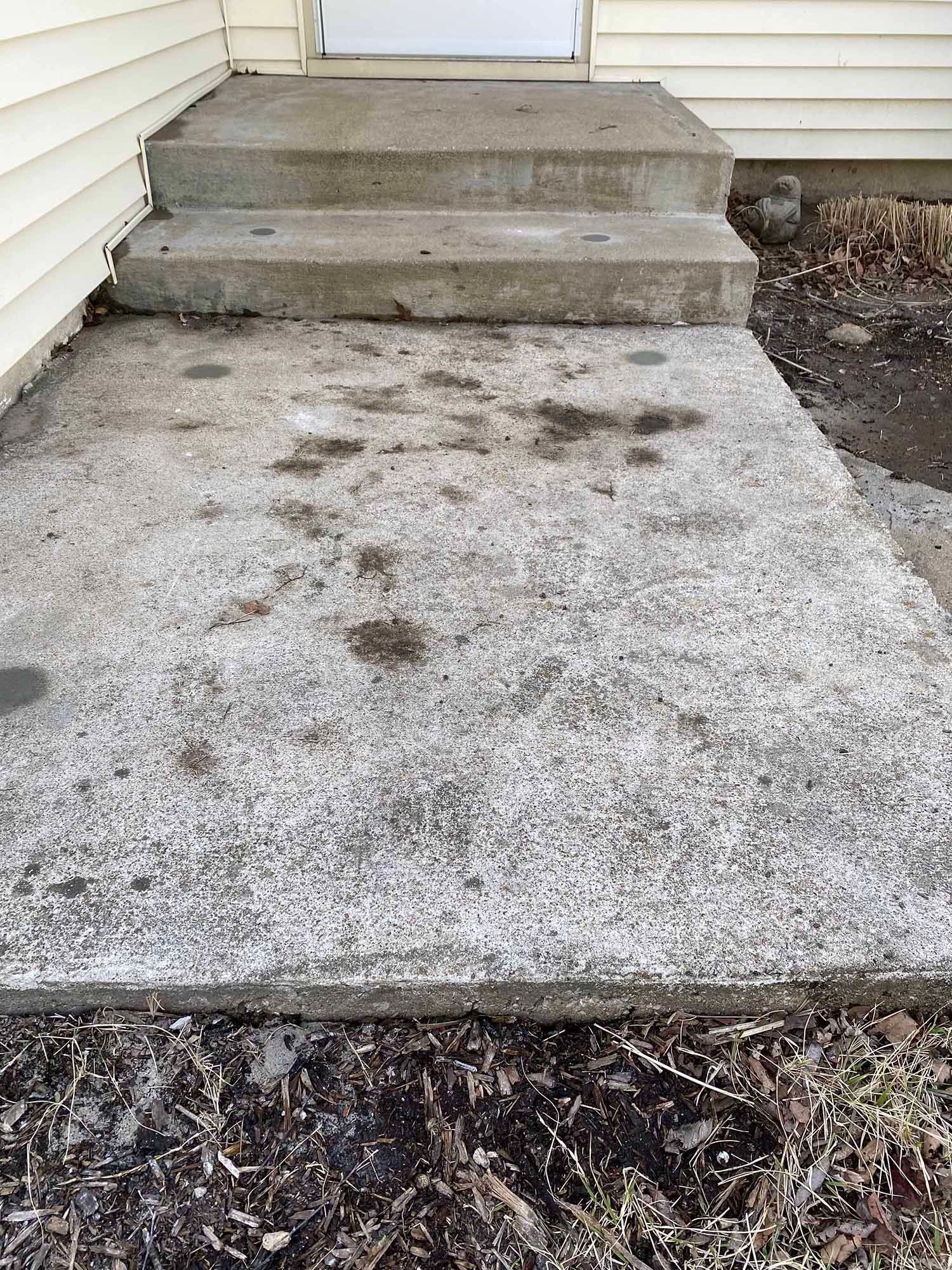 A concrete walkway with steps leading up to a house.