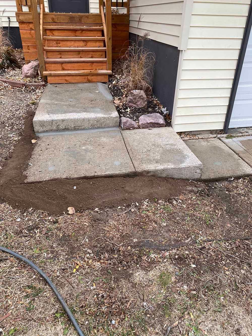 A concrete walkway is being built in front of a house.