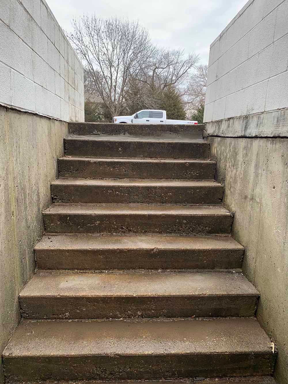 A set of concrete stairs leading up to a white wall.