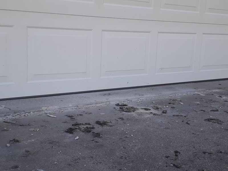 A white garage door is sitting on top of a concrete driveway.
