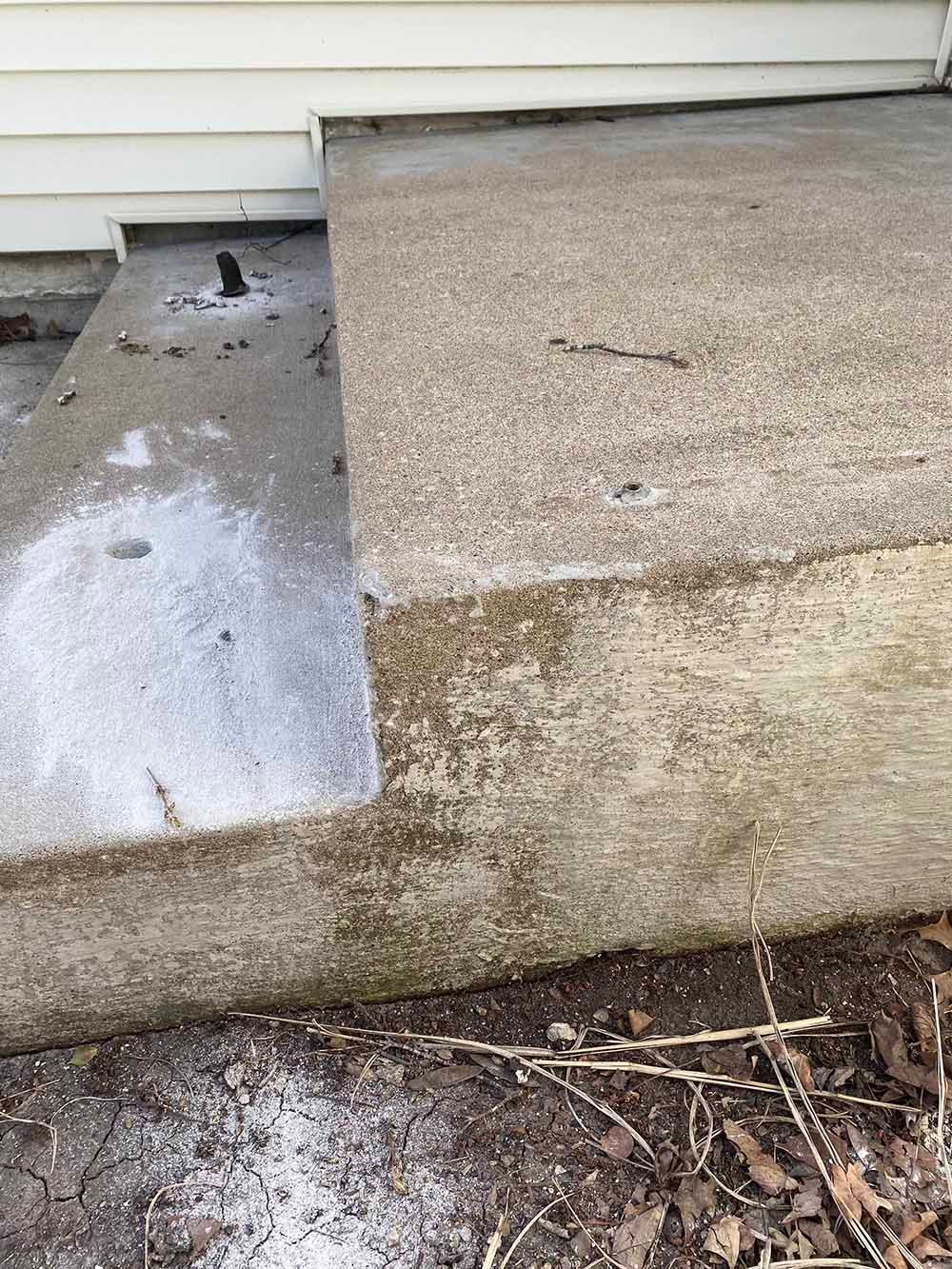 A close up of a concrete step next to a house.