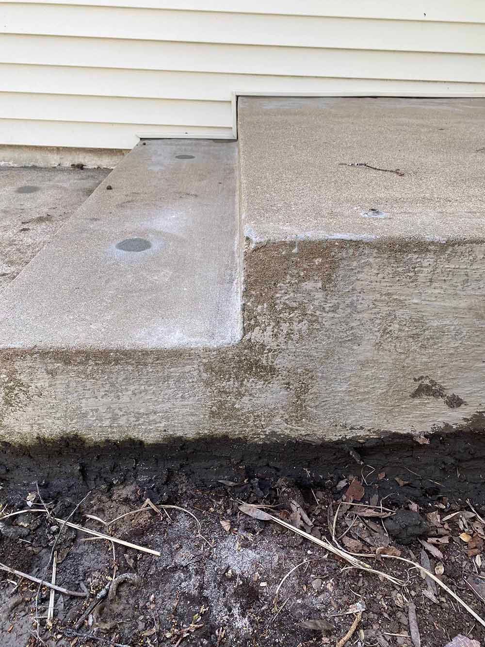 A close up of a concrete step next to a house.