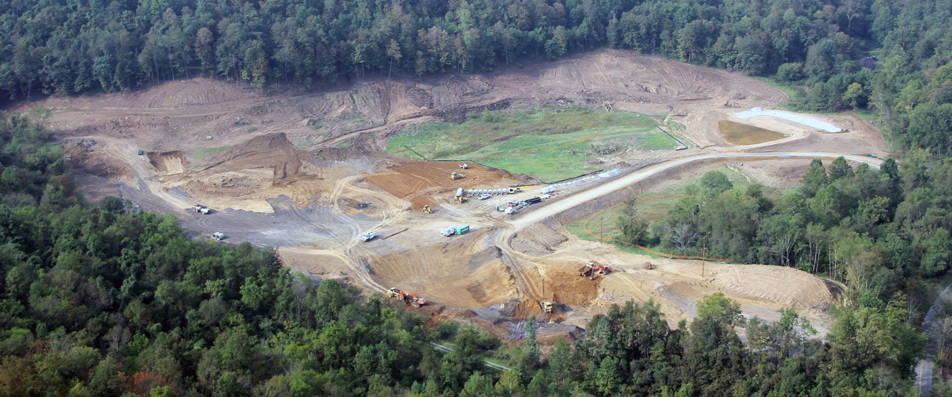 Aerial view of a large open-pit mine surrounded by dense green forest.