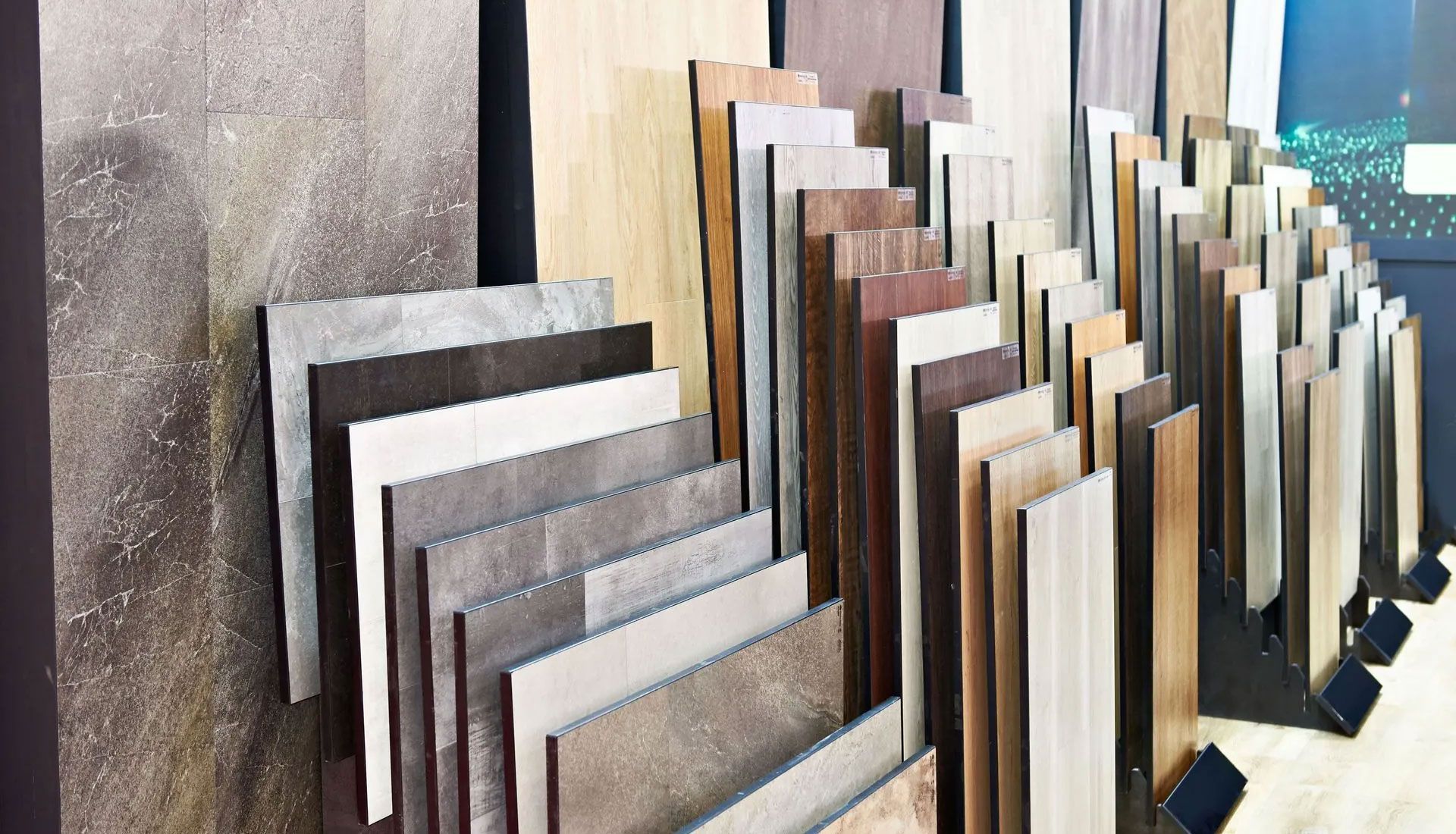 A showroom display featuring a diverse range of vertical stone, wood, and laminate tile samples organized in rows.