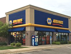 A napa auto parts store with a pepsi machine in front of it.