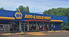 A napa auto & truck parts store with a parking lot in front of it.