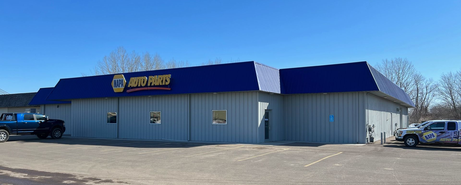 A white building with a blue awning and a sign that says auto parts