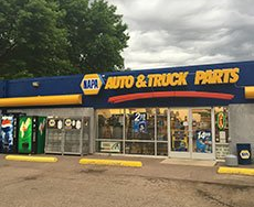 A napa auto & truck parts store with a pepsi machine in front of it.