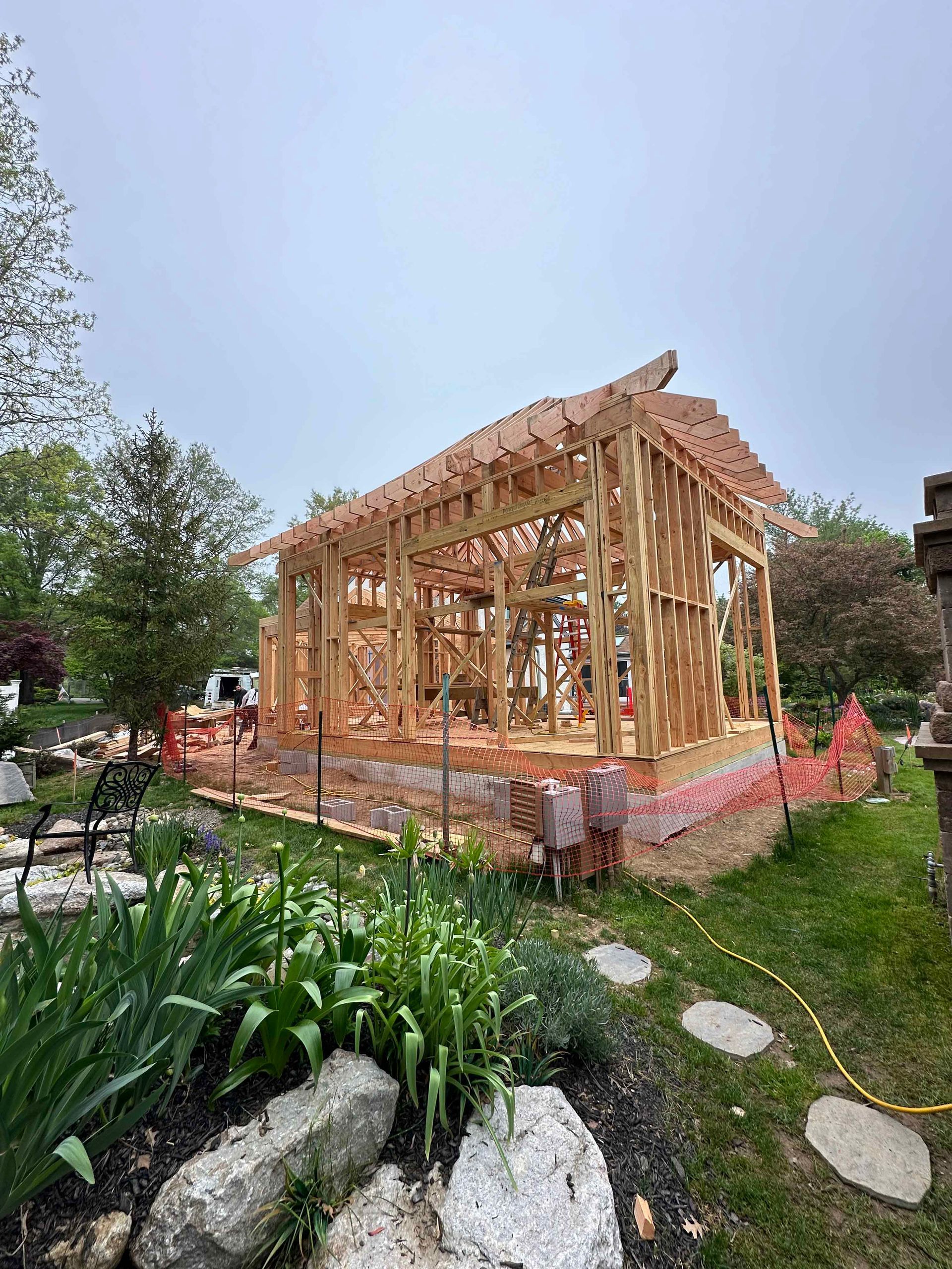 A wooden house is being built in a backyard.