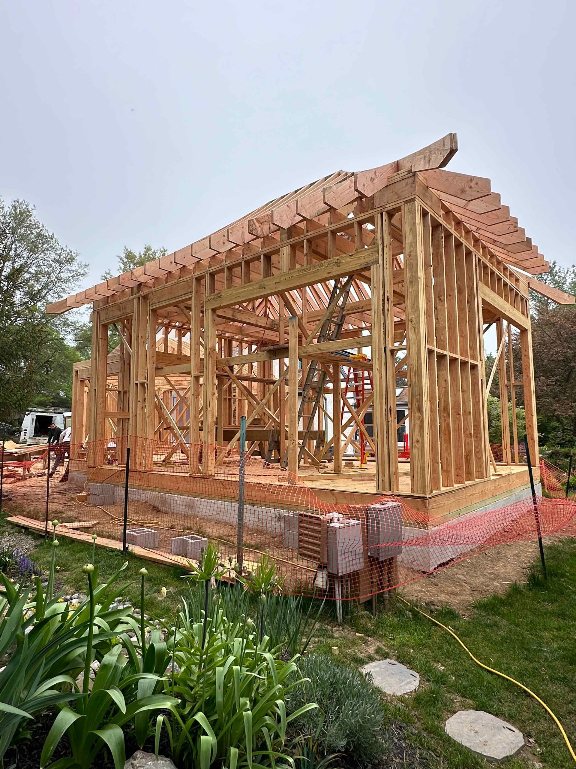 A wooden house is being built in a backyard.
