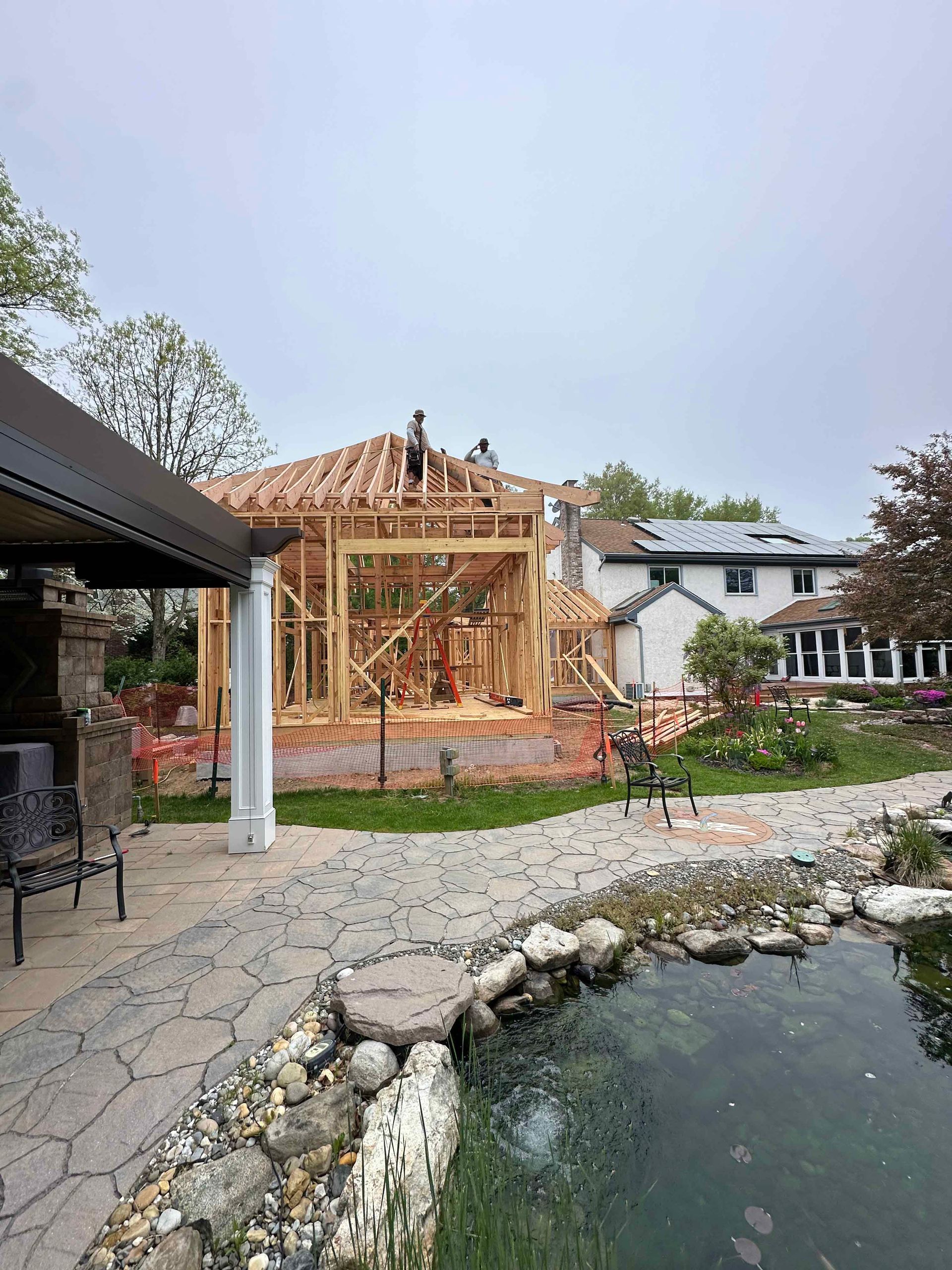 A house is being built in a backyard next to a pond.