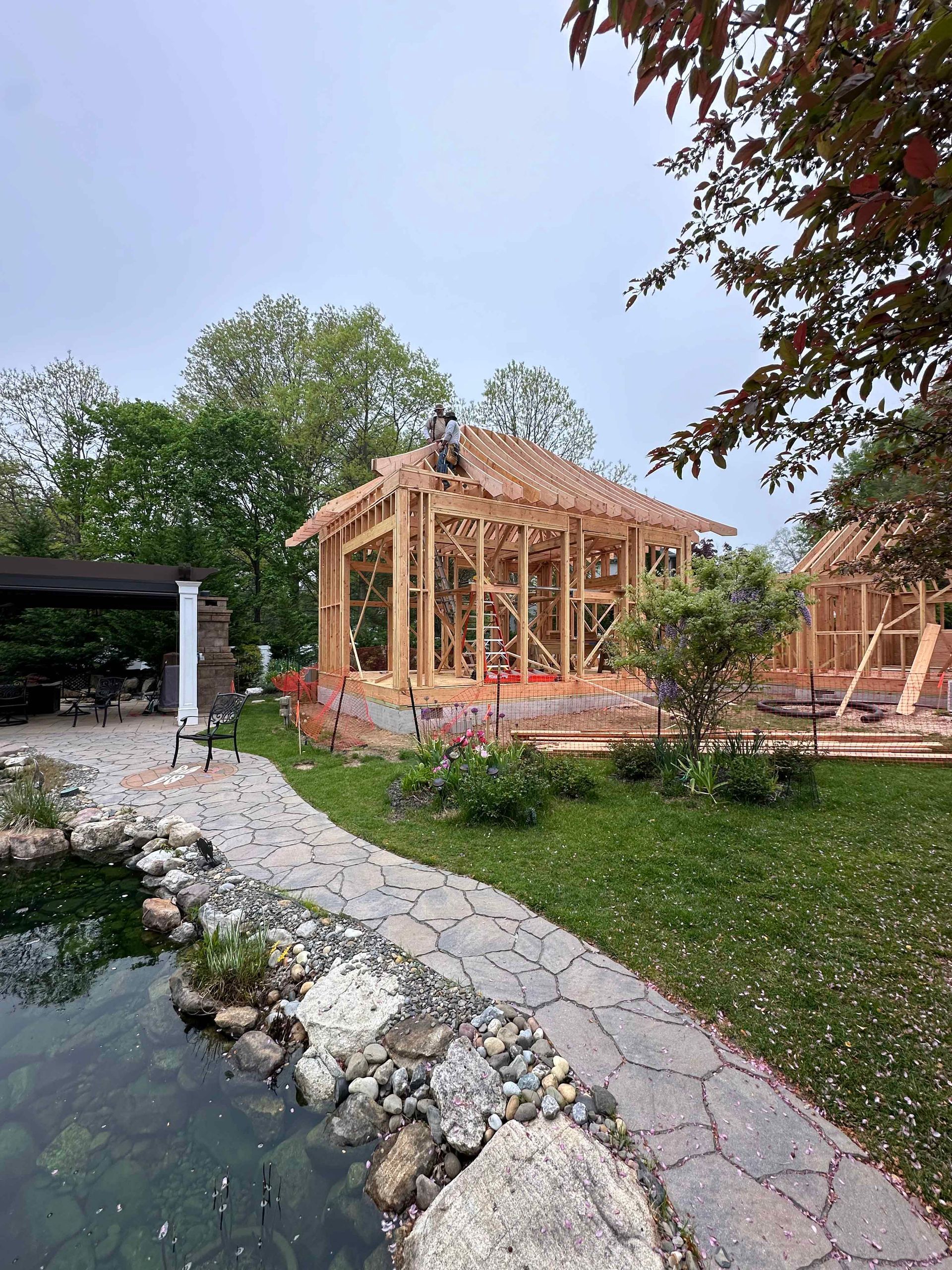 A house is being built in a backyard next to a pond.