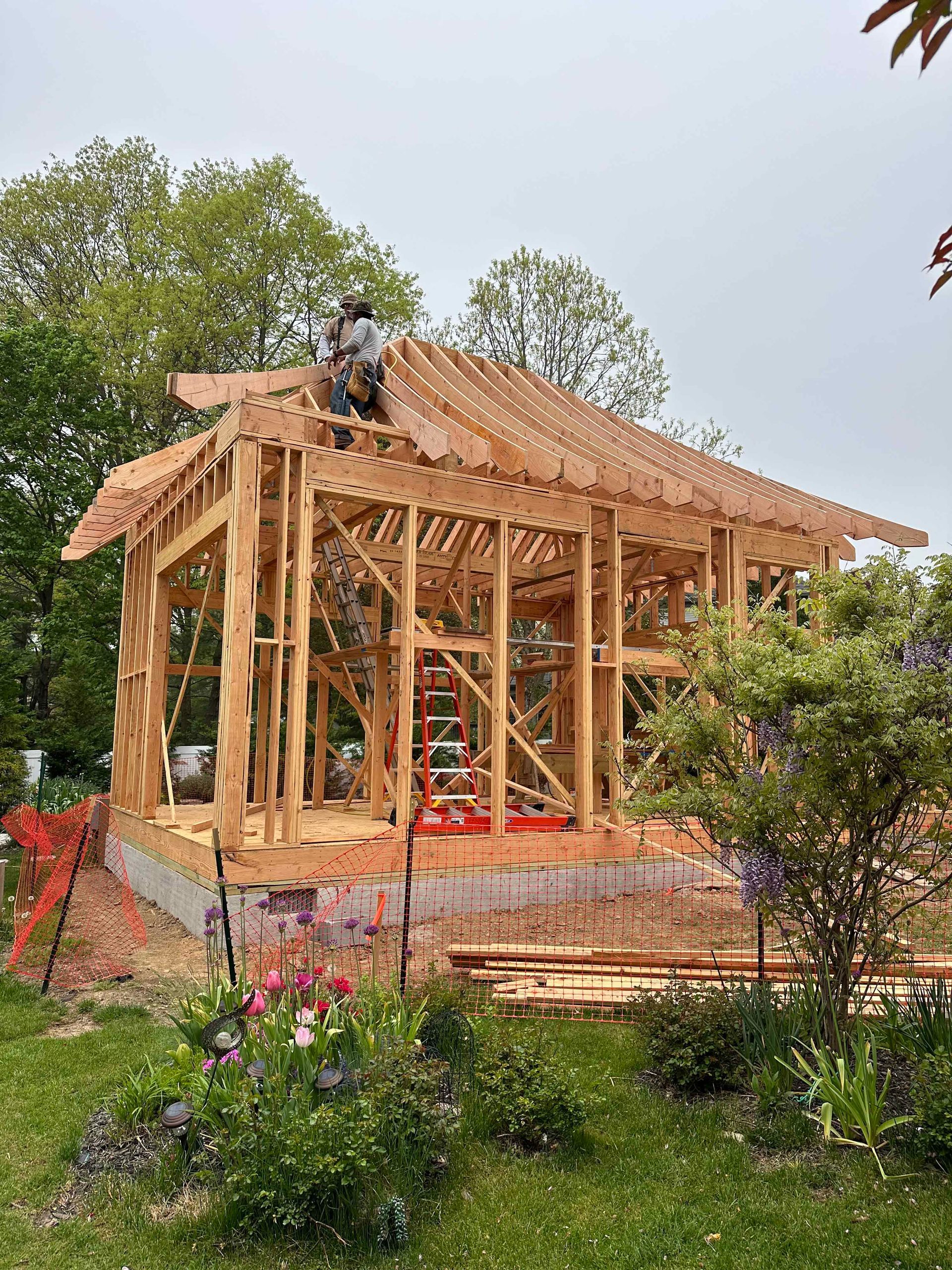 A man is working on the roof of a wooden house under construction.