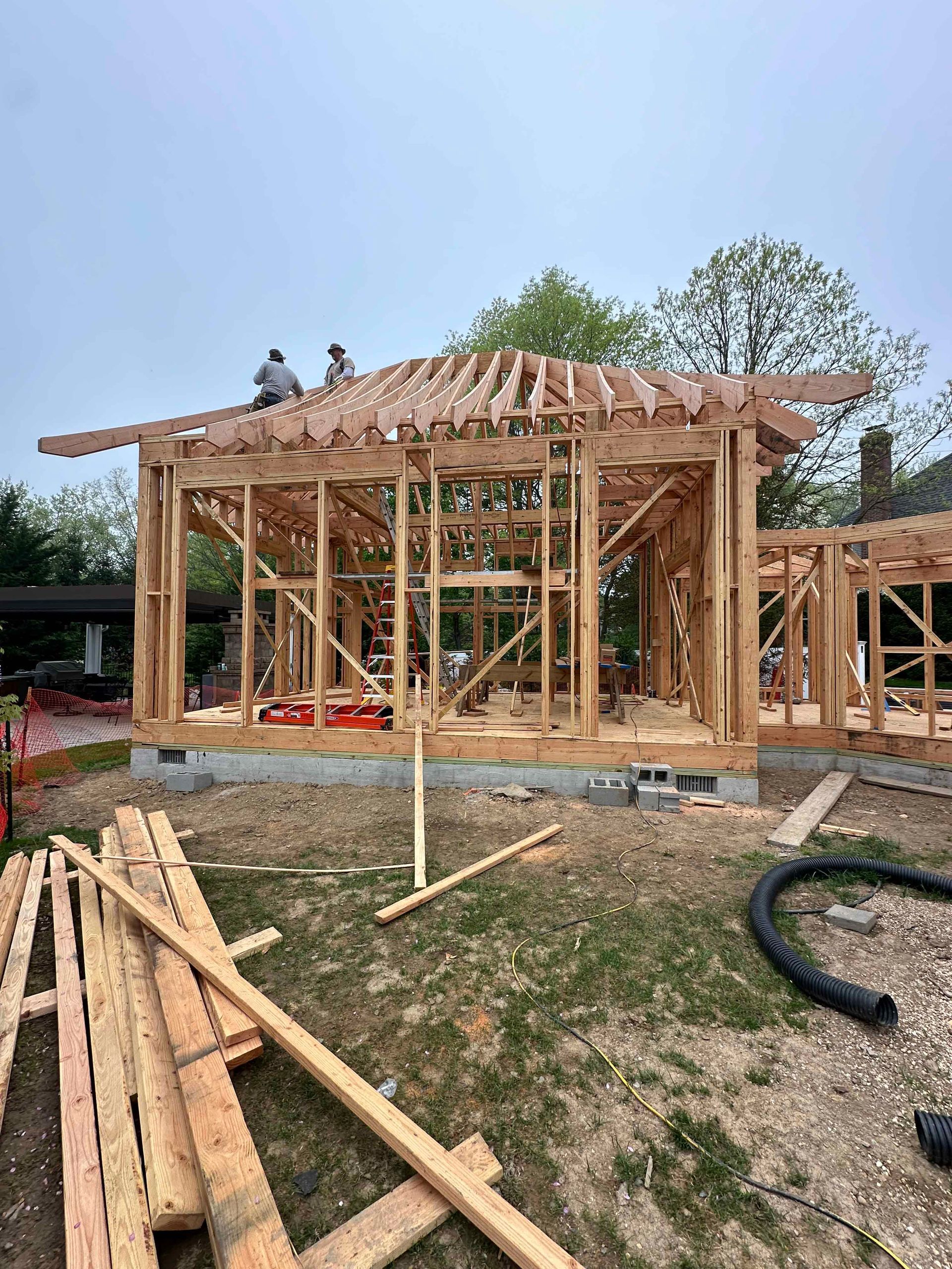 A wooden house is being built in the middle of a field.
