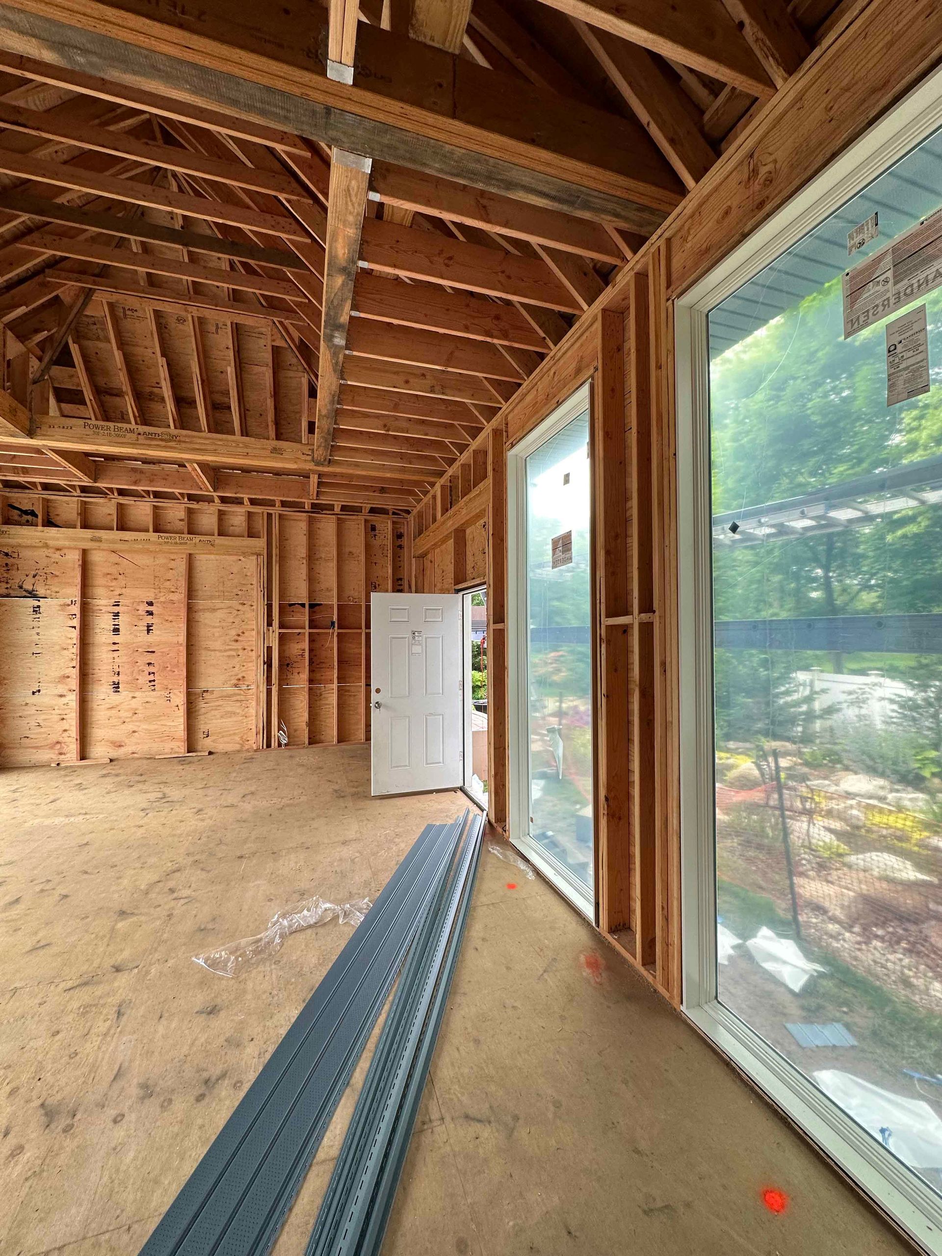 A room with a lot of windows and a door in a house under construction.