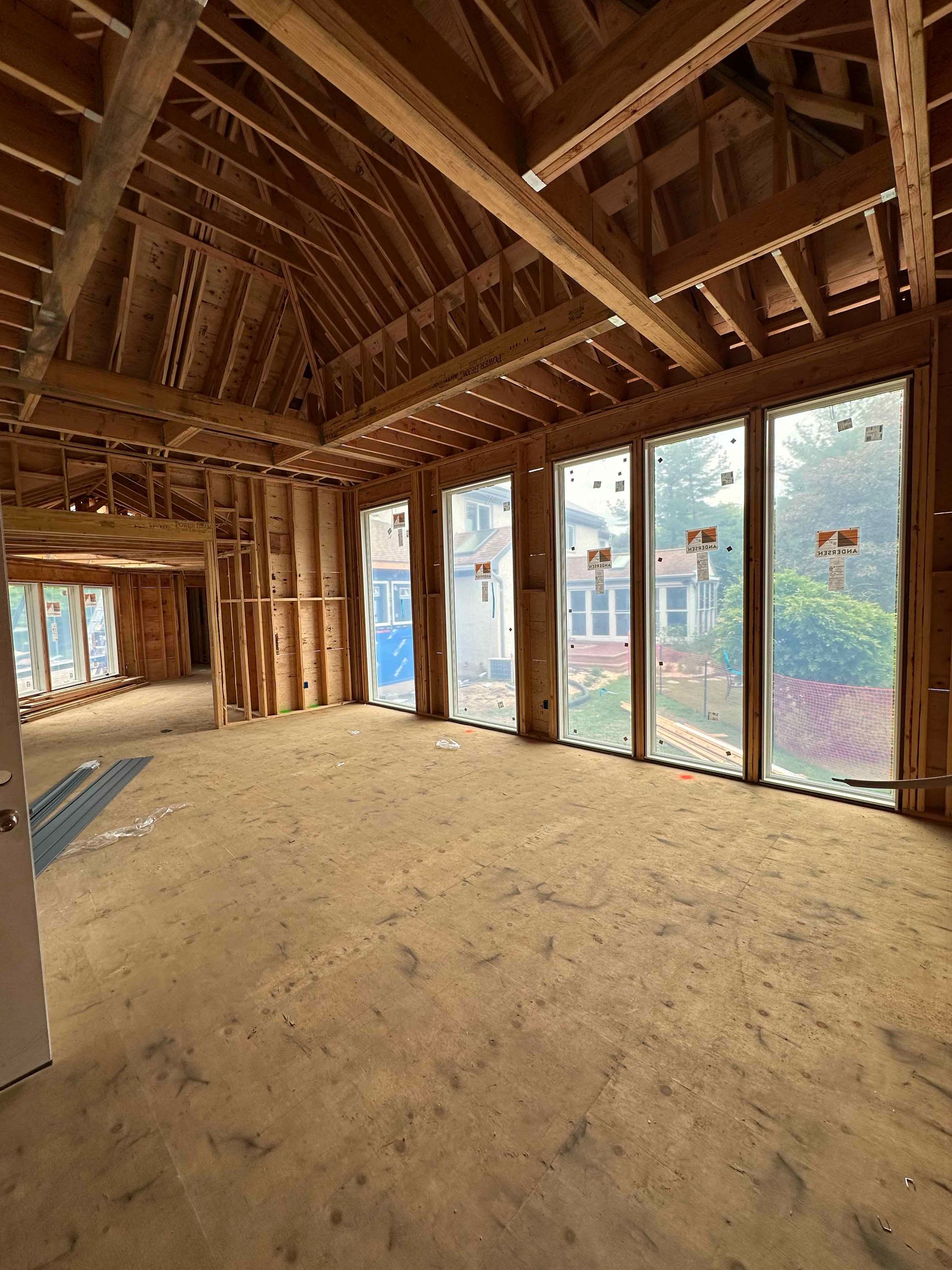 A large empty room with lots of windows and wooden beams.
