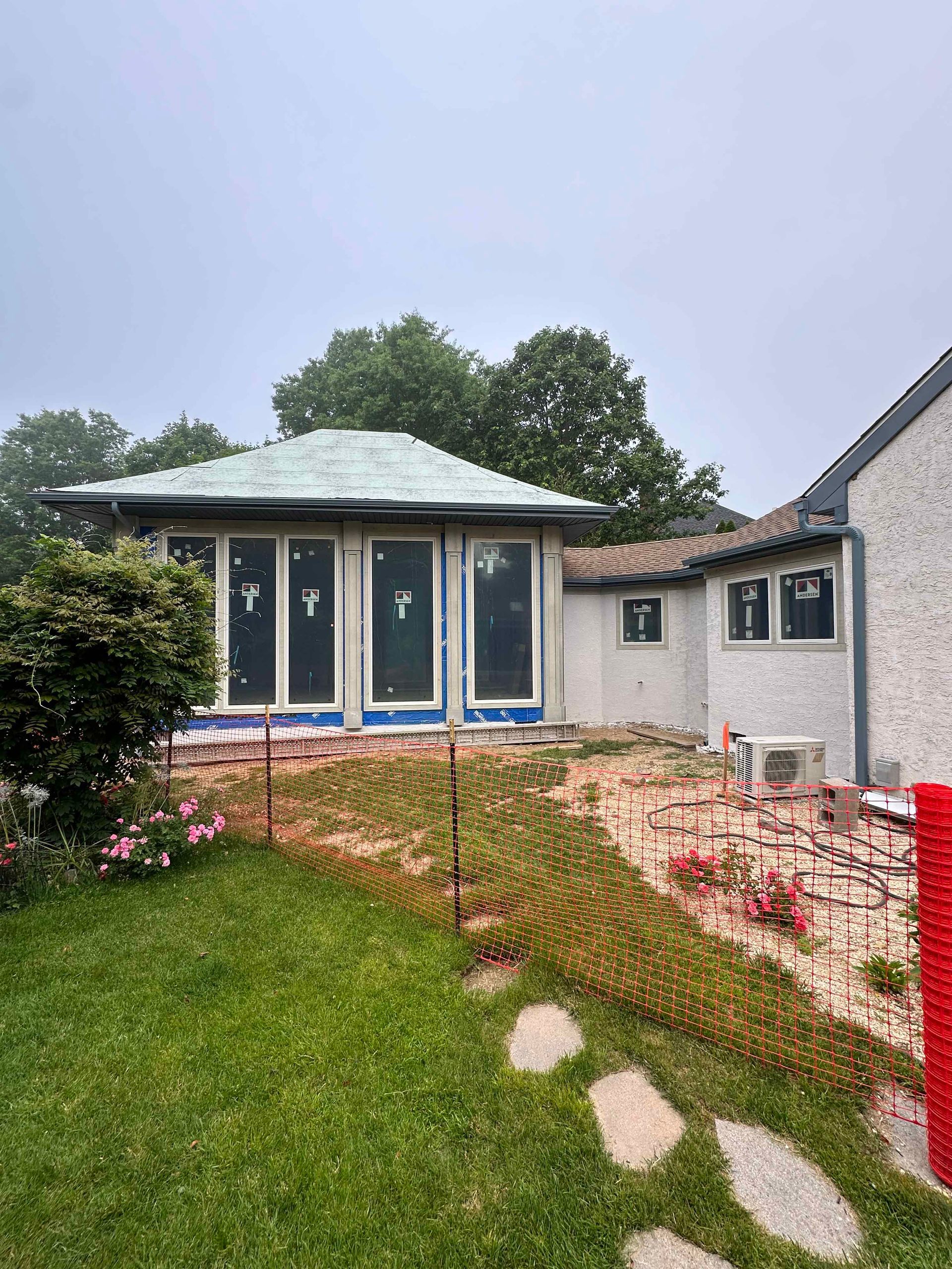 A house with a green roof is being built in a backyard.